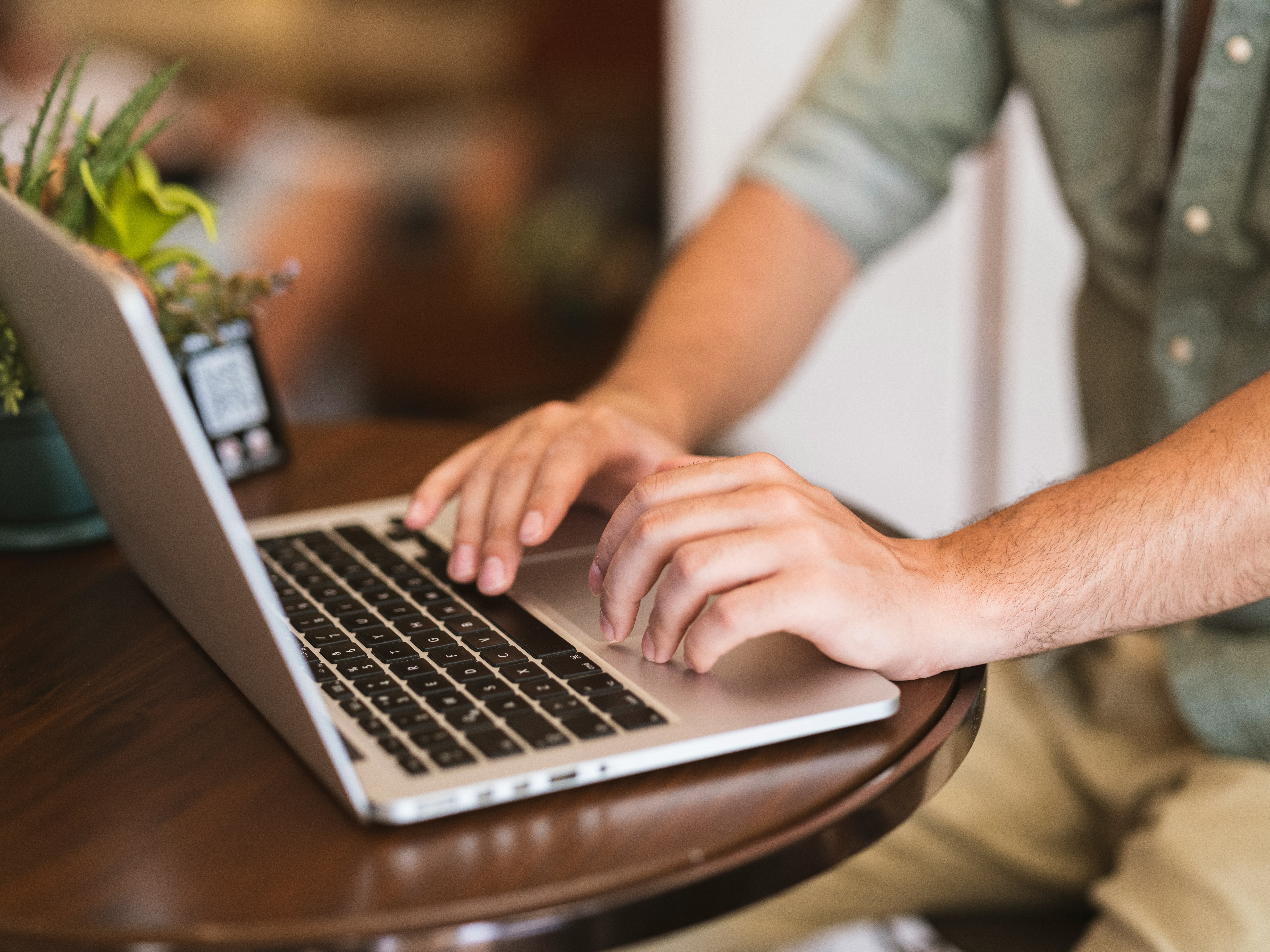 Person typing on a laptop at a wooden desk.